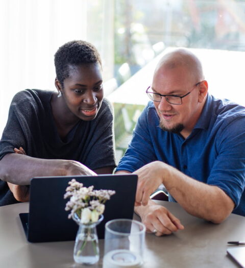 Gideon and Dominique from The Werks sitting behind a laptop, pointing to the screen